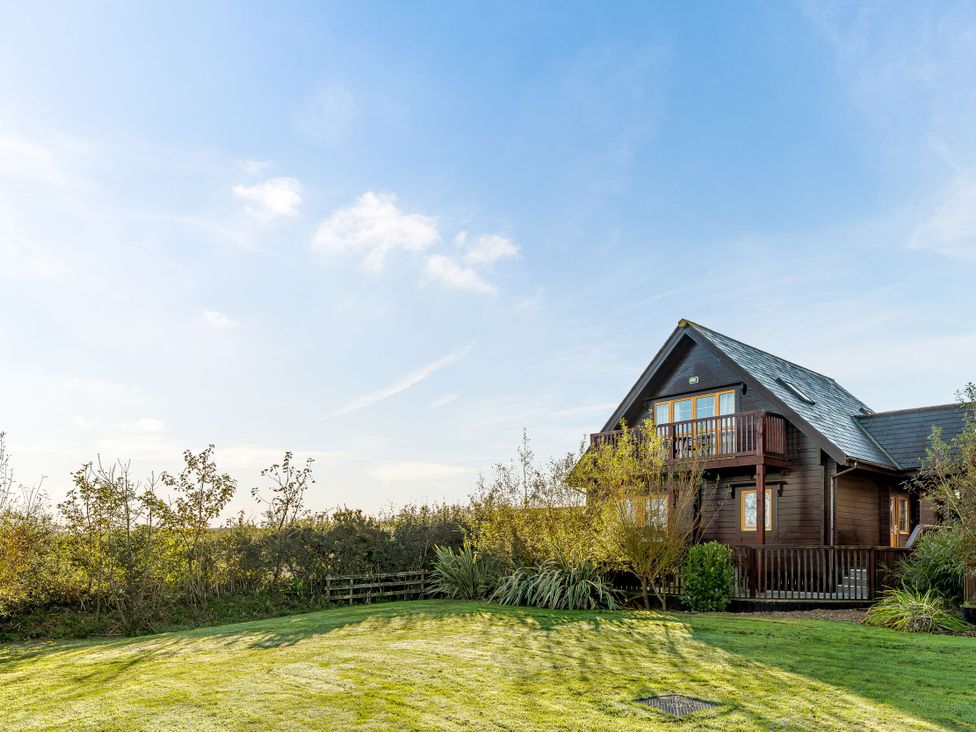 A house with a balcony and surrounding greenery at Scandinavian Hot Tub Lodge in Portreath