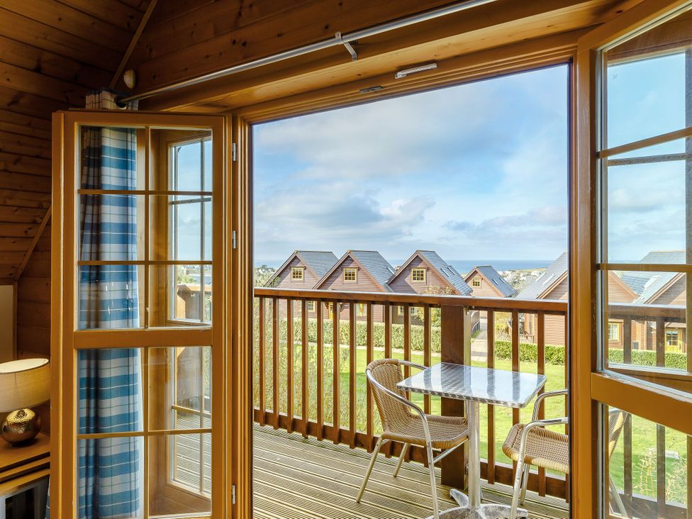 A balcony with a table and chairs overlooking houses at Scandinavian Hot Tub Lodge Pet Portreath