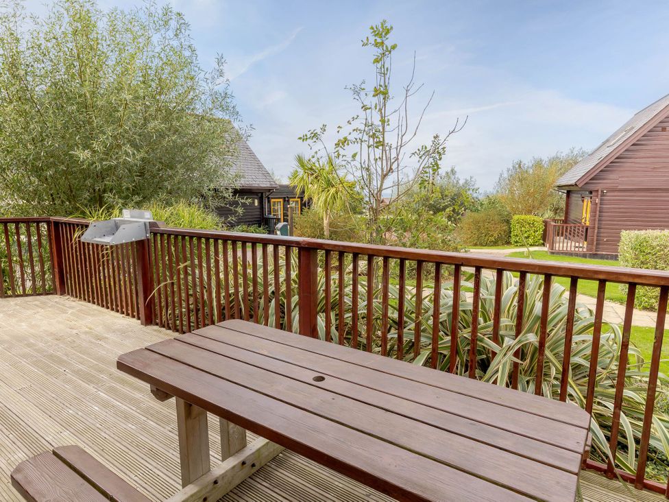 A deck area with a table and barbecue at Scandinavian Lodge Pet in Portreath