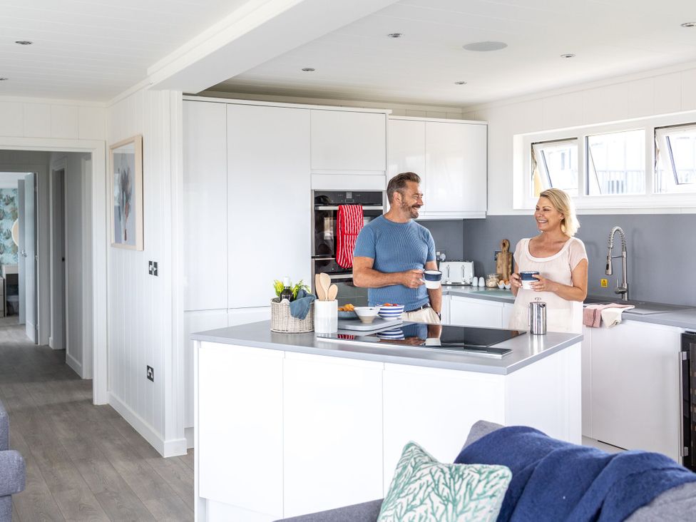 A kitchen with a couple talking over a kitchen island at Signature Lodge Pet 8 Portreath