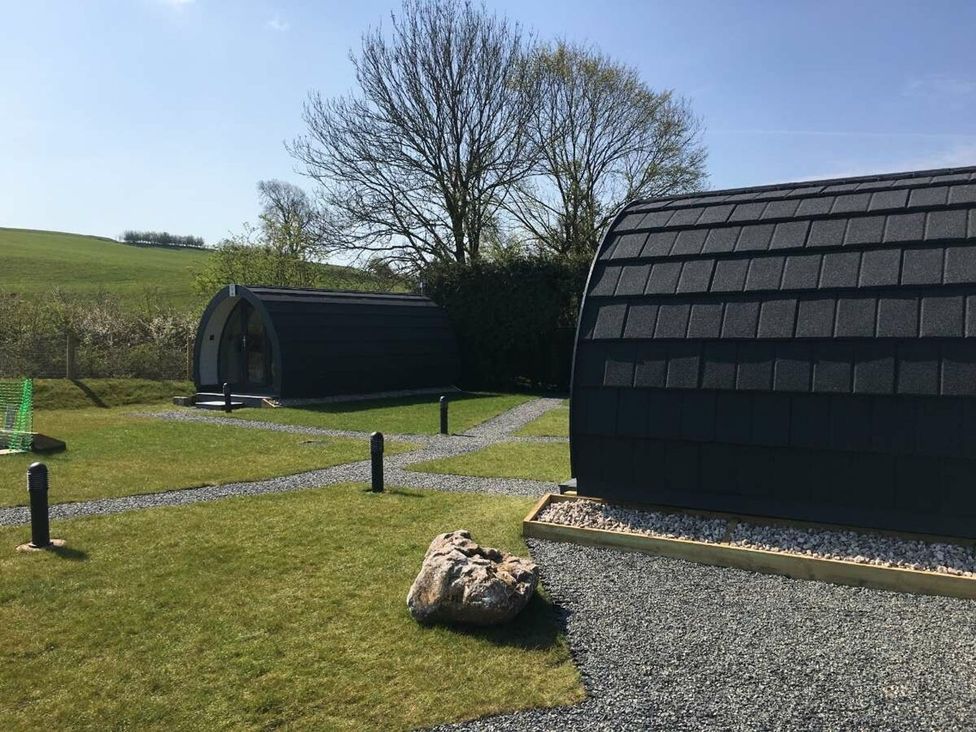 Cabins in an outdoor area with grass and a pathway at Pod 3 (No Pets) Carnforth
