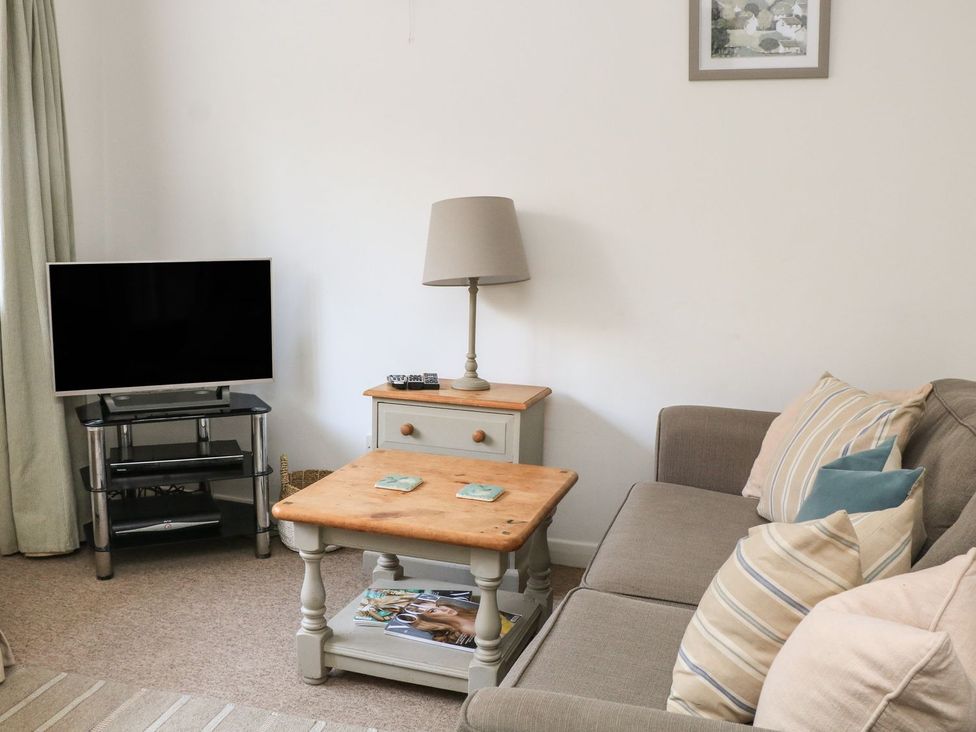 A living room with a sofa, tv, and coffee table at 3 Moult Farm Cottages in Salcombe