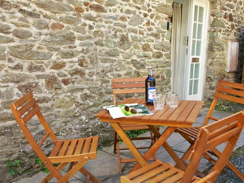 A wooden table with chairs and a bottle at 3 Moult Farm Cottages Salcombe