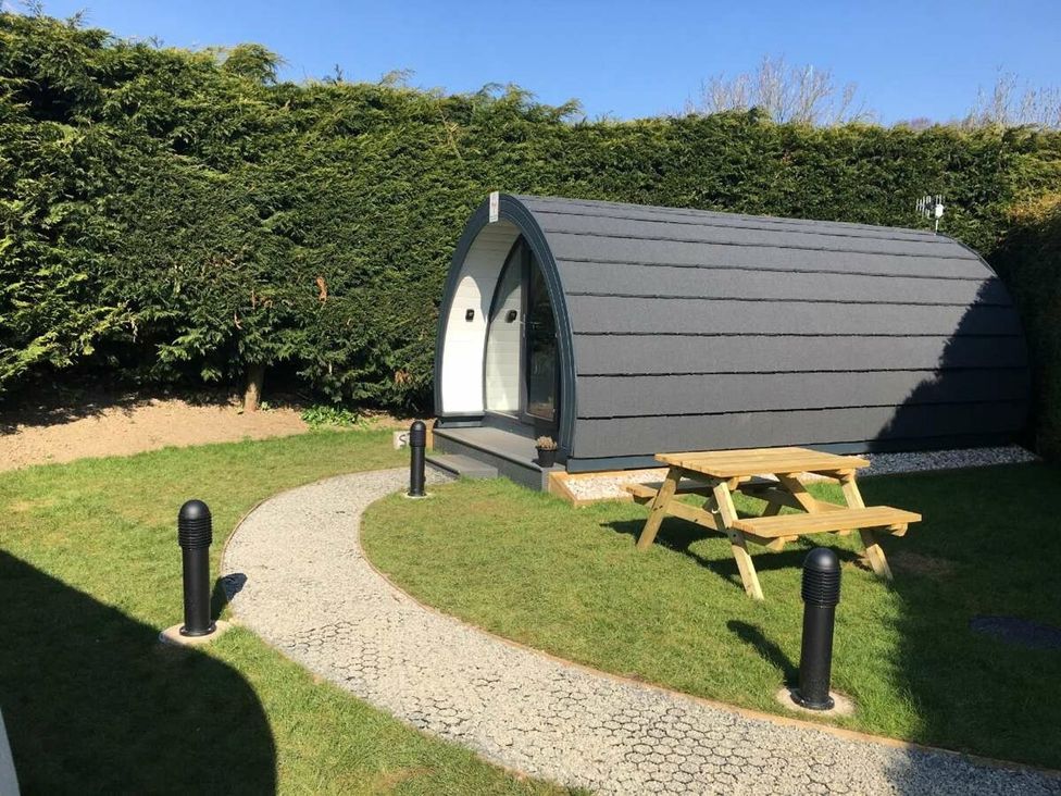 A cabin in a garden with a picnic table and pathway at Pod 4 (No Pets) in Carnforth