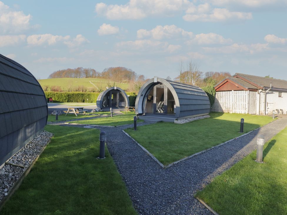 Three accommodation pods with a pathway and grass at Pod 5 (Pet Friendly) Tewitfield