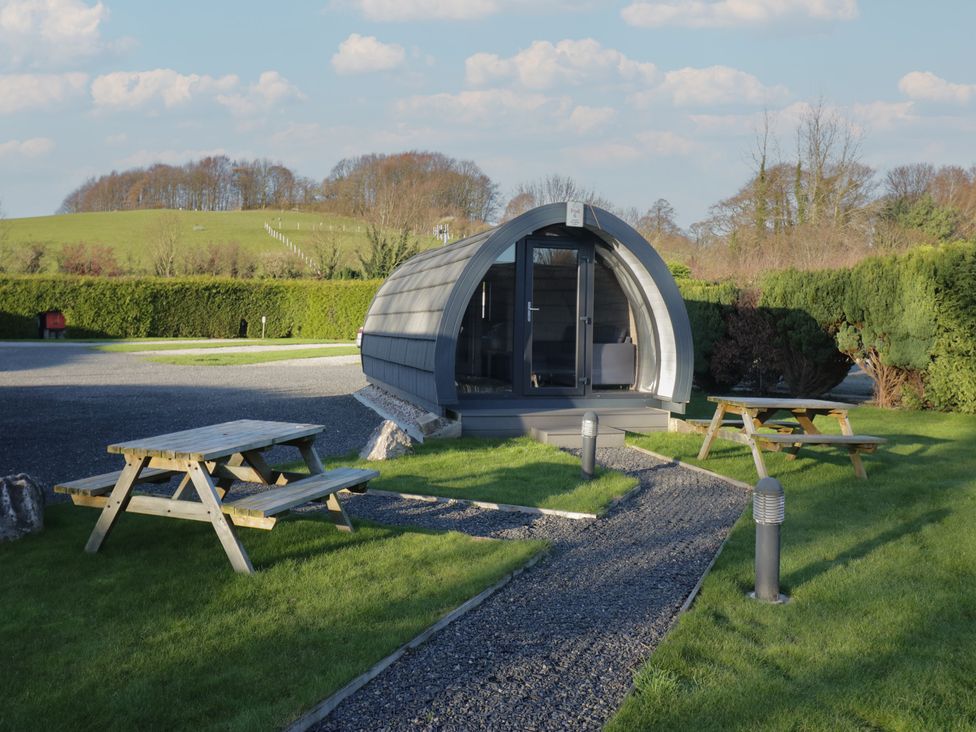 An outdoor area with a glamping pod and picnic tables at Pod 6 (No Pets) Tewitfield