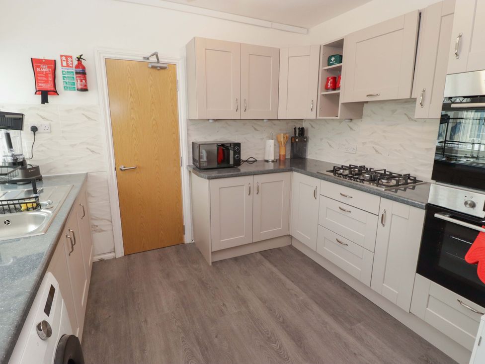 A kitchen with cabinets, a microwave, and a stove at William's Place in Barry