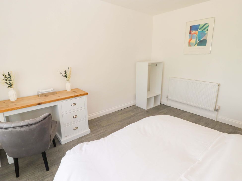 A bedroom with a bed, desk, chair, and radiator at William's Place in Barry
