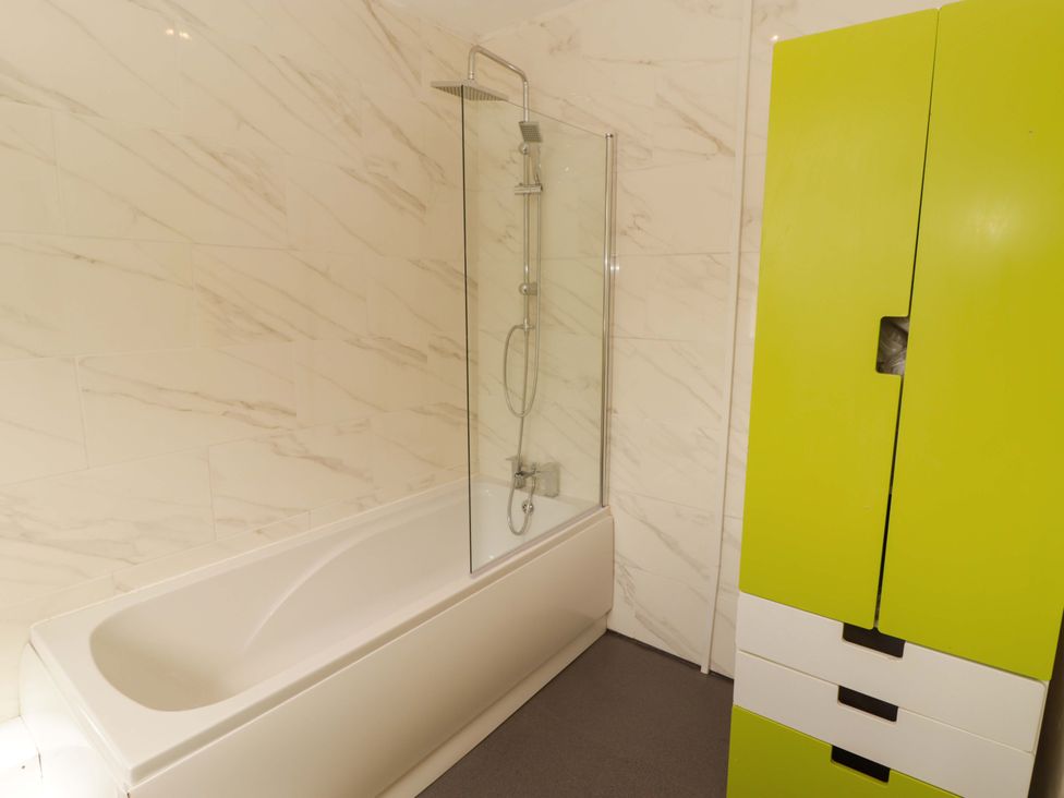 A bathroom with a bathtub and a green cabinet at William's Place in Barry