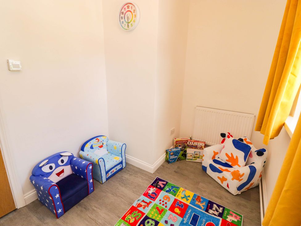A playroom with children's chairs and board games at William's Place in Barry