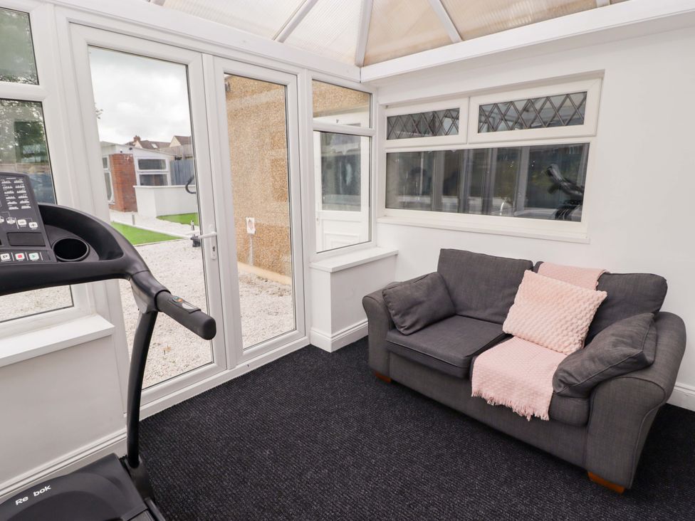 A conservatory with a treadmill and a sofa at William's Place in Barry
