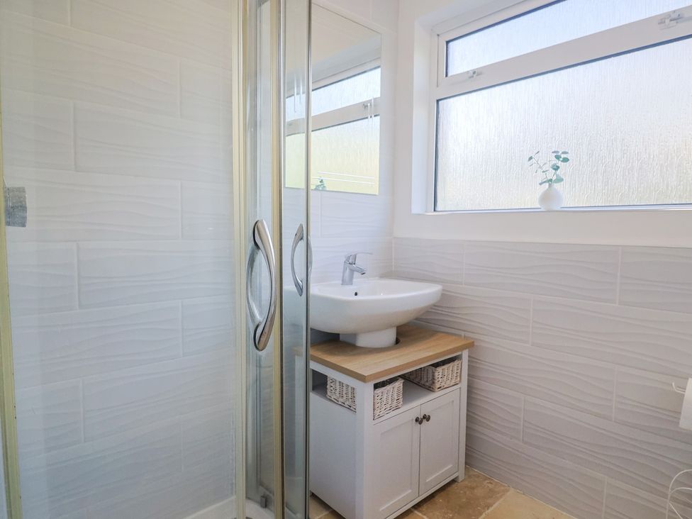 A bathroom featuring a shower, sink and storage at Fluta in Seaton