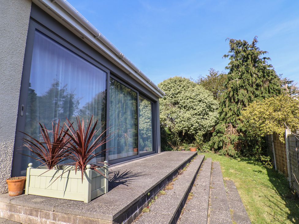 A garden with steps leading to glass doors at Fluta in Seaton