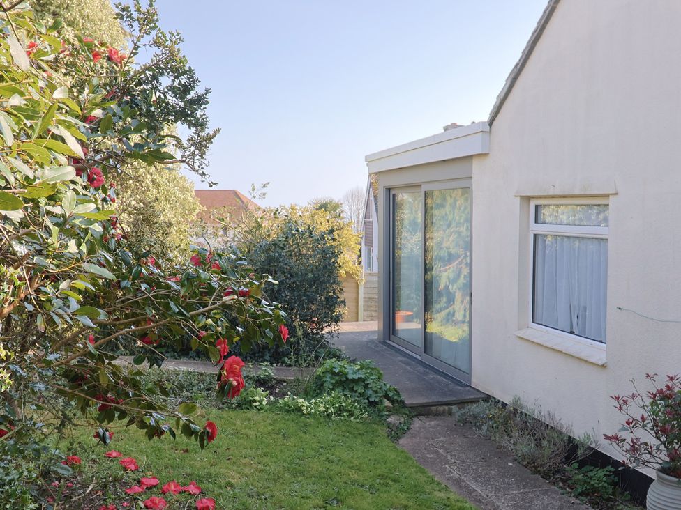 An outdoor area with flowering plants and a glass door at Fluta in Seaton