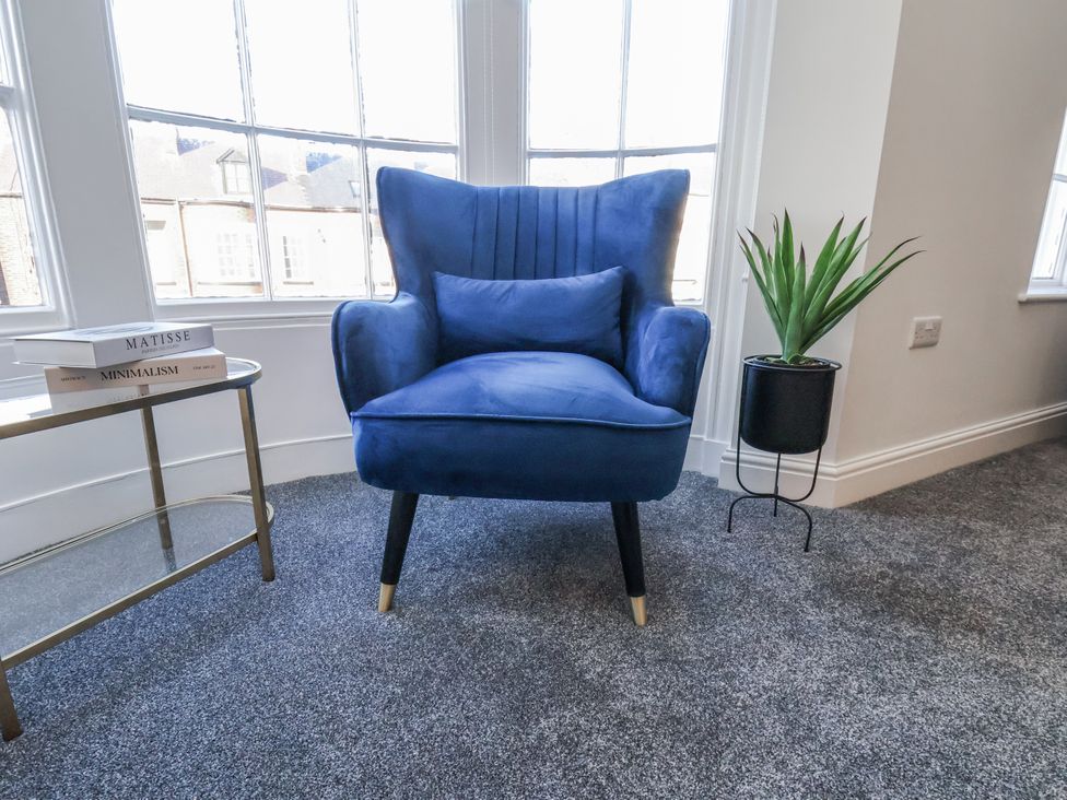 A living room with a blue chair and side table at 2 bed Scarborough