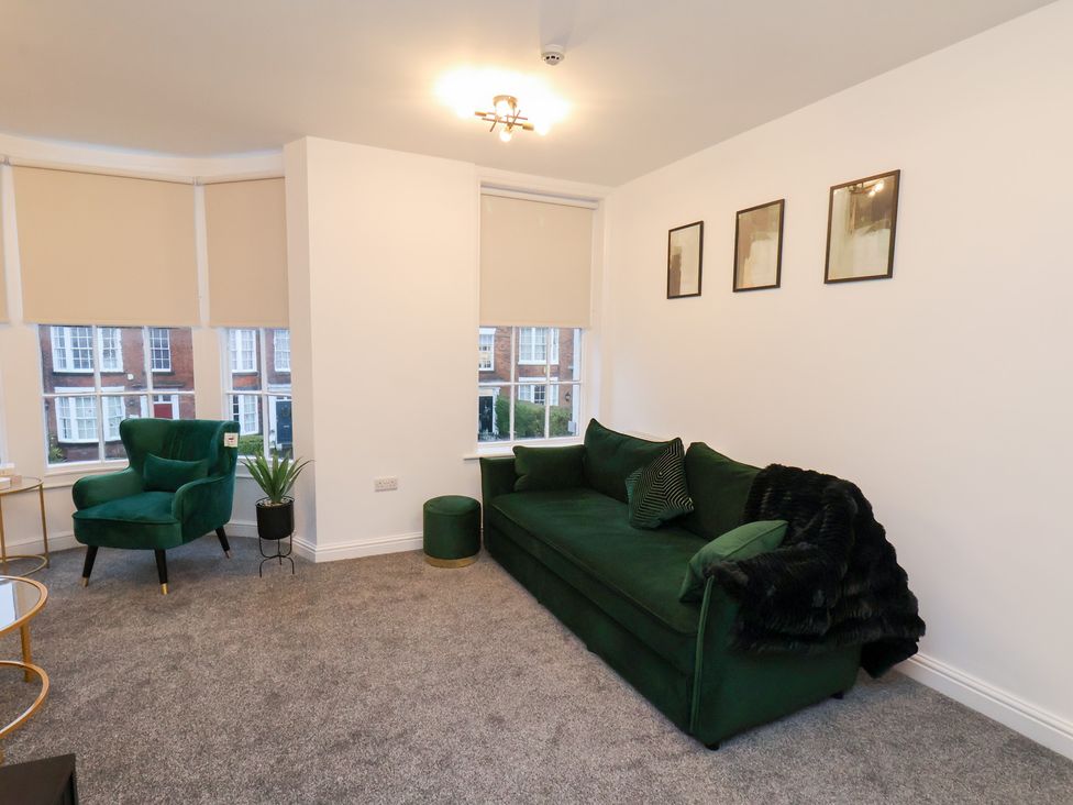 A living room with a green sofa and armchair at Maxwell View, Scarborough