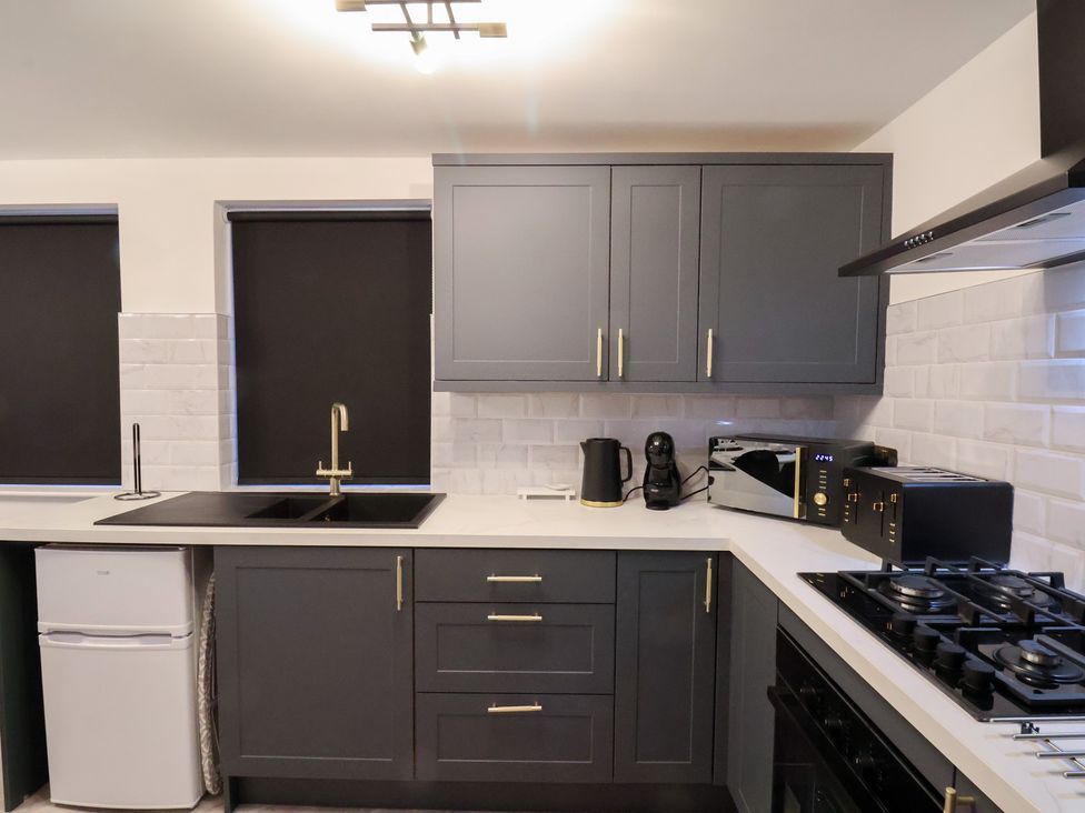 A kitchen with cabinets, sink, kettle, and microwave at Maxwell View in Scarborough