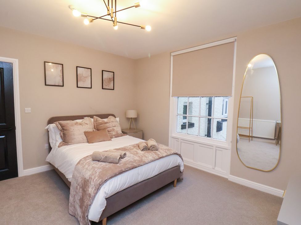 A bedroom with a bed, mirror, and window at Maxwell View in Scarborough
