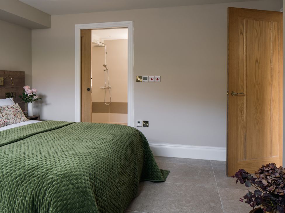 A bedroom with a bed and an attached shower at The School House in Newton Abbot