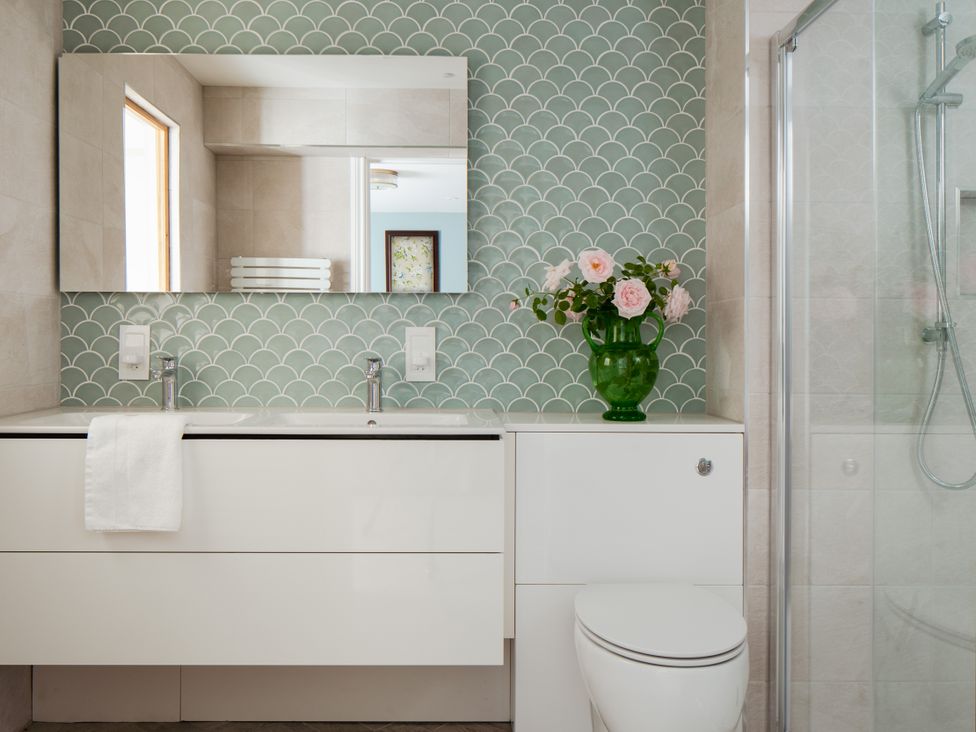 A bathroom with a sink, mirror, and flowers in a vase at The School House in Newton Abbot
