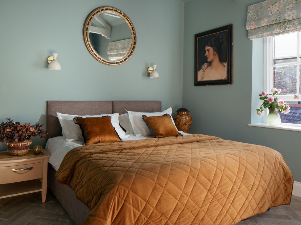 A bedroom with a bed and decorative items at Upper School House Newton Abbot
