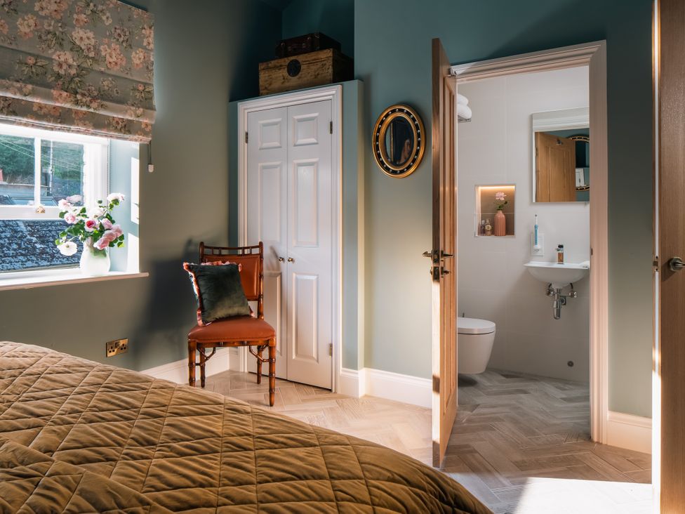 A bedroom with a chair, bed and an adjoining bathroom at Upper School House in Newton Abbot