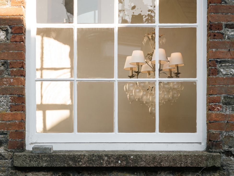 A window with a chandelier visible from outside at Upper School House in Newton Abbot