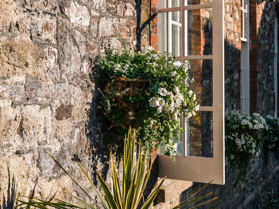 A window with flowers on a stone wall at Upper School House in Newton Abbot