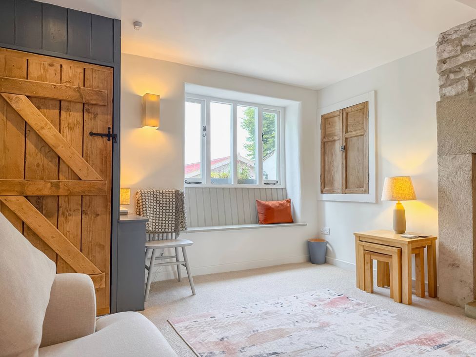 A living room with a wooden door and a window seat at 7 Litton Slack in Tideswell