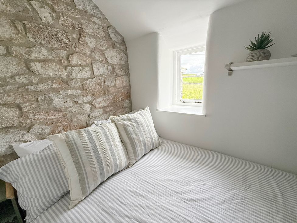 A bedroom with a bed and stone wall at 7 Litton Slack in Tideswell