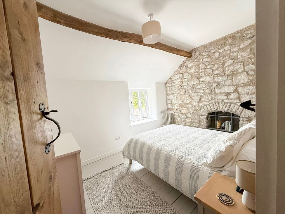 A bedroom with a bed and wall with stone features at 7 Litton Slack in Tideswell