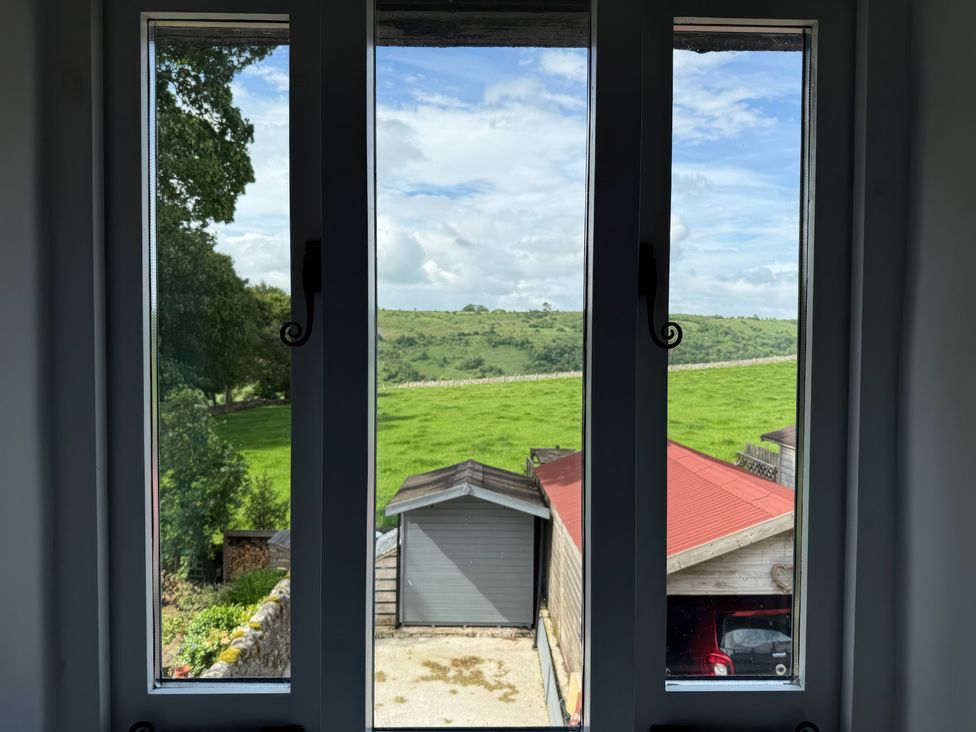 A view from a window showing a green field and outbuildings at 7 Litton Slack Tideswell