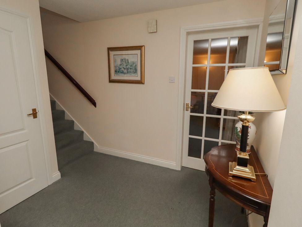 A hallway with a staircase and lamp at Grange Cottage in Belford