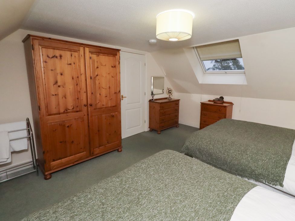 A bedroom with two beds and wooden furniture at Grange Cottage in Belford