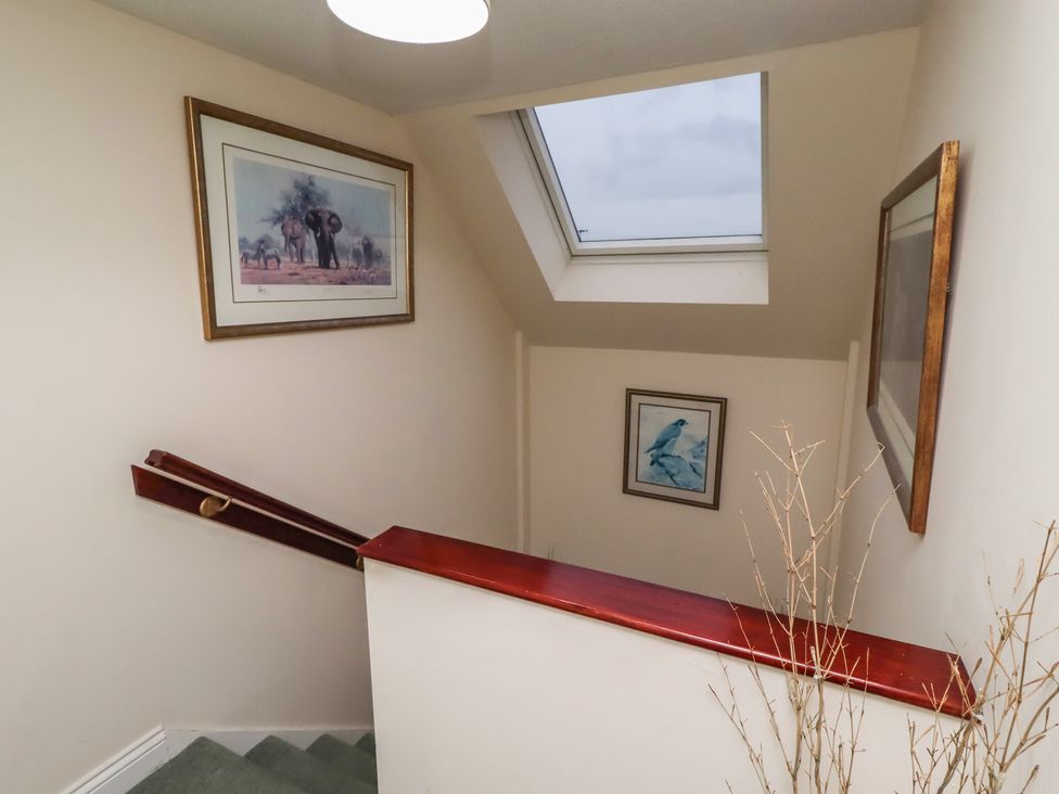 A staircase with paintings on the wall at Grange Cottage in Belford