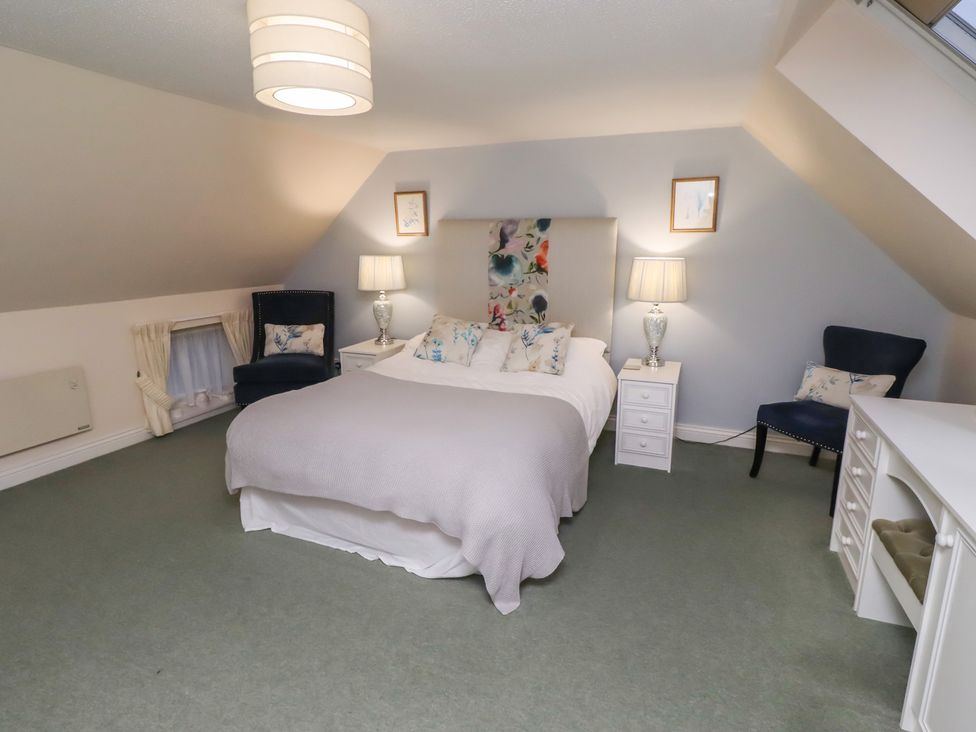 A bedroom with a bed and two chairs at Grange Cottage in Belford