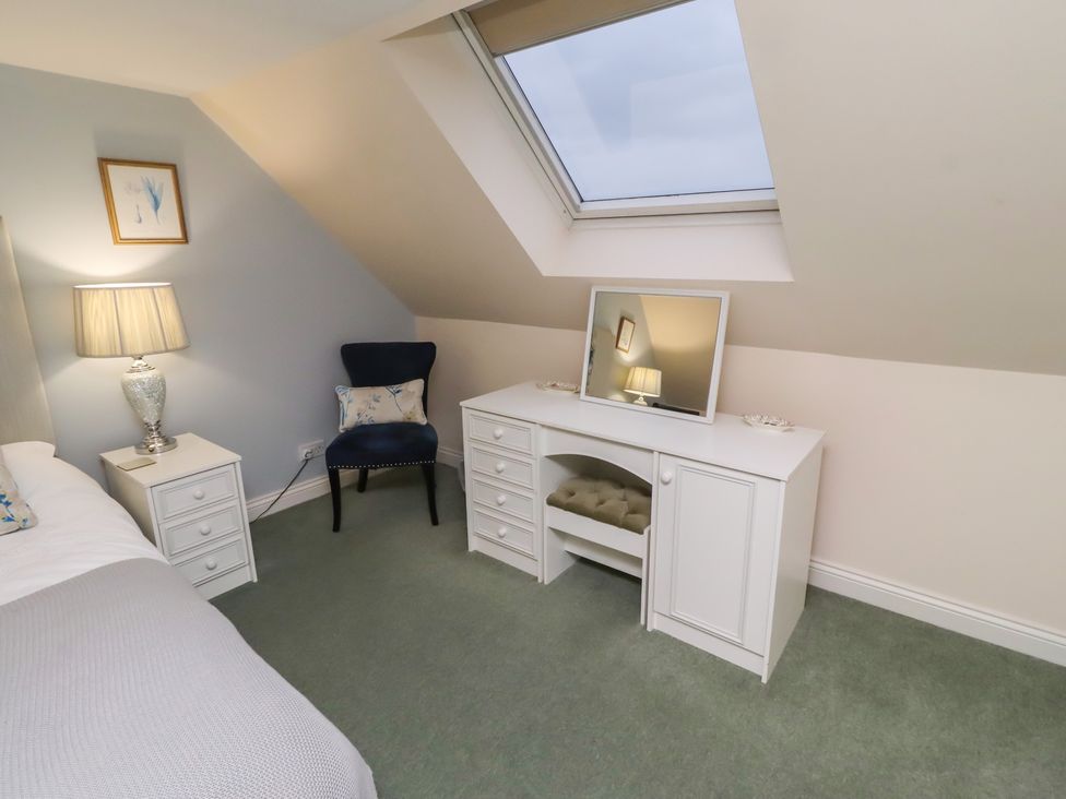 A bedroom with a bed, lamp, chair, and vanity at Grange Cottage in Belford