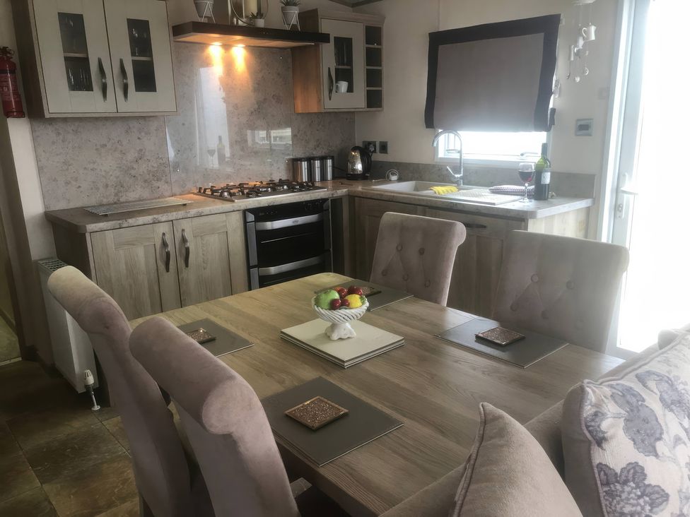 A dining room with a table and kitchen elements at 62 Guddlebeck in Lakeland Leisure Park, Flookburgh