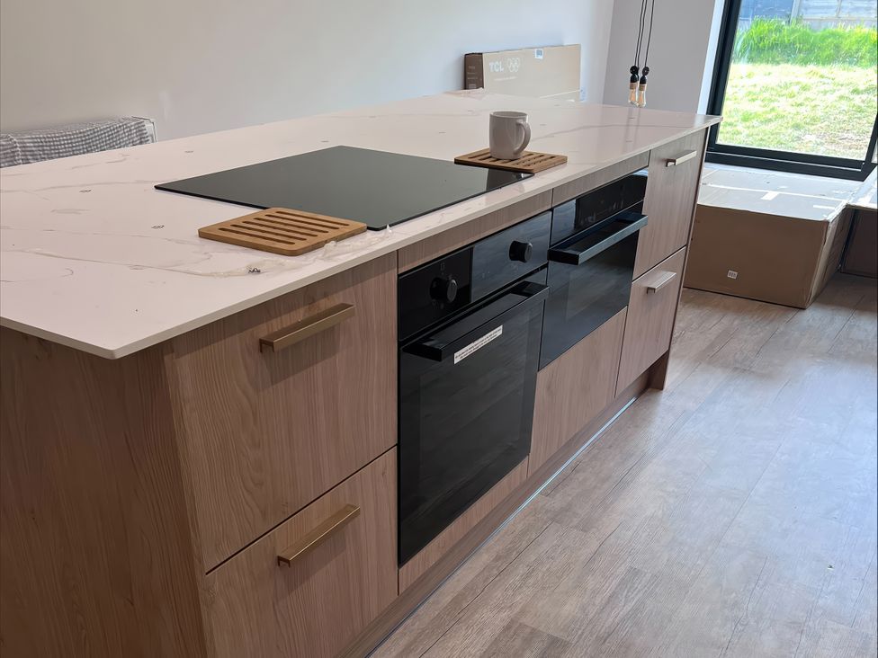 A kitchen with an island featuring a cooktop and ovens at 81 Lon Gogarth Benllech