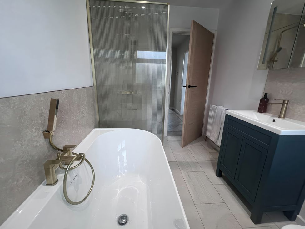 A bathroom with a bathtub, sink, and shower at 81 Lon Gogarth, Benllech