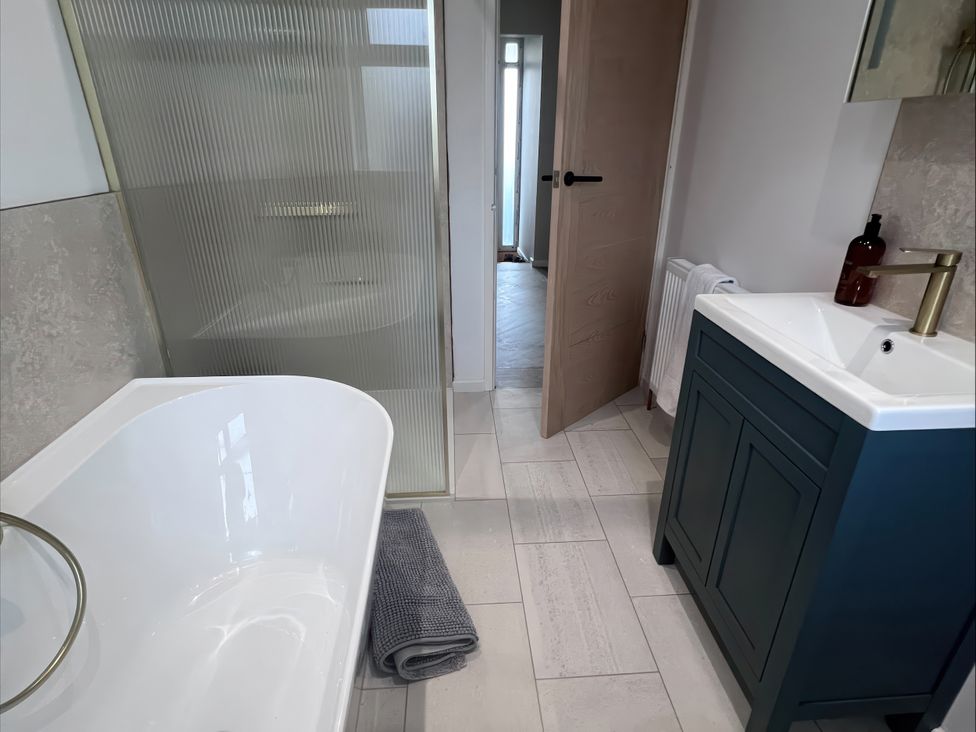 A bathroom with a bathtub and sink at 81 Lon Gogarth in Benllech