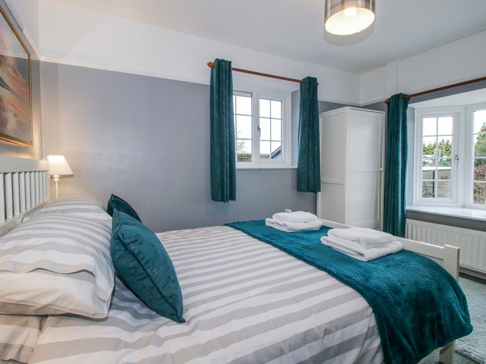 A bedroom with a bed and windows at The Rumbles