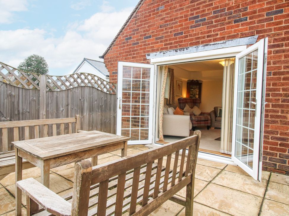 An outdoor patio with a wooden table and chairs at The Rumbles in 