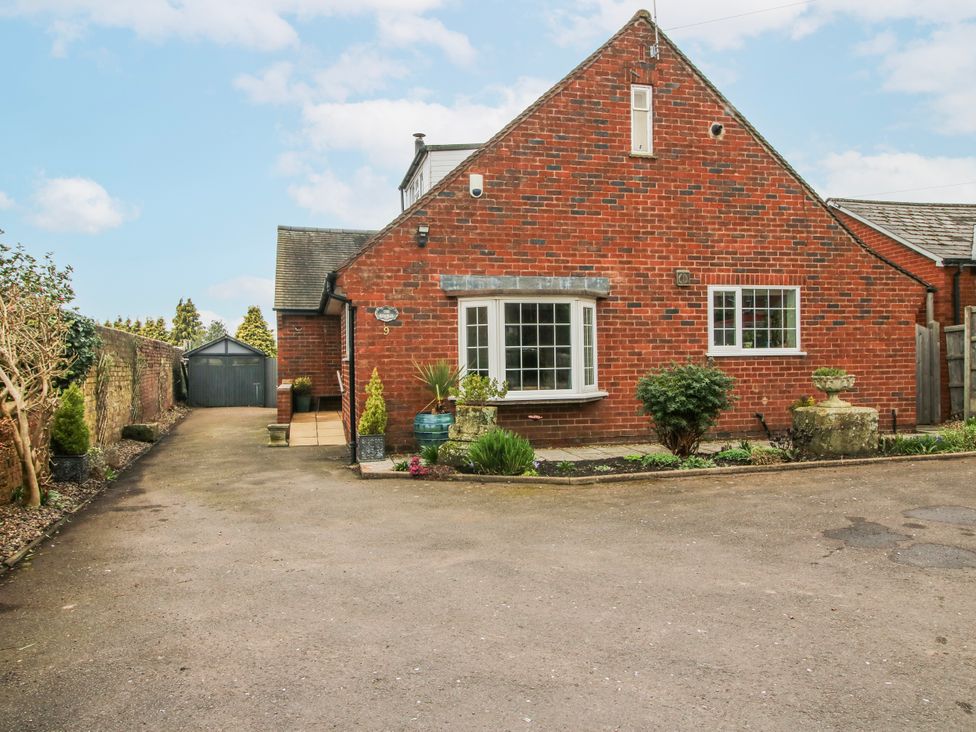 A brick house with garden features and driveway at The Rumbles