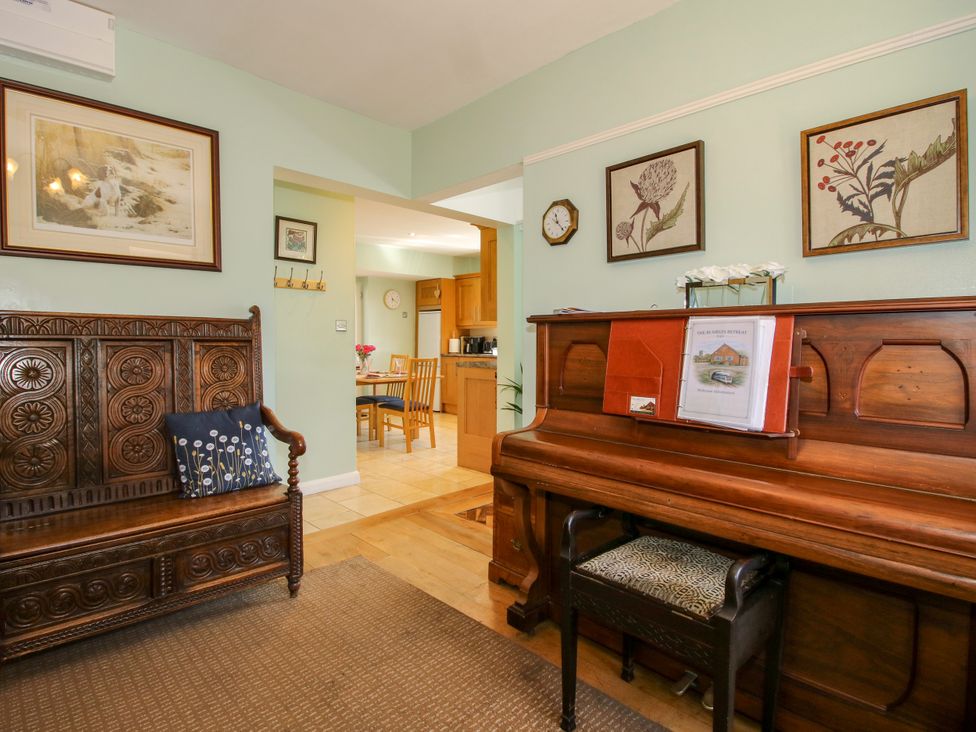 A living room with a bench and piano at The Rumbles in Ludlow