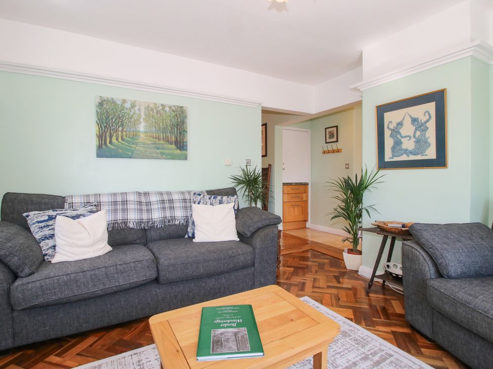 A living room with a sofa, wooden table, and plants at The Rumbles in Ludlow