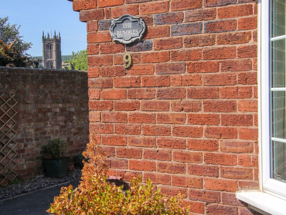 An outdoor view of The Rumbles with a brick wall and house number in Ludlow