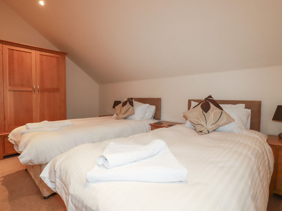 A bedroom with two beds and a wardrobe at 65 Benasa Lodge near St Columb Major