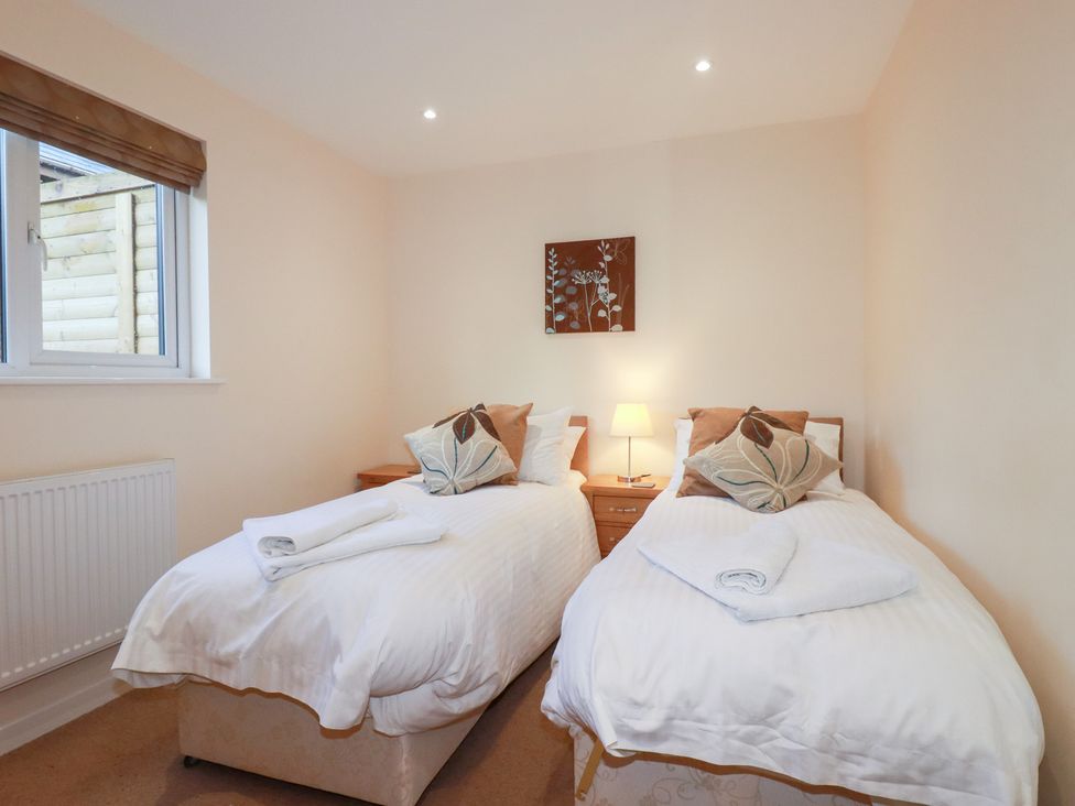 A bedroom with twin beds and a lamp at 65 Benasa Lodge near St Columb Major