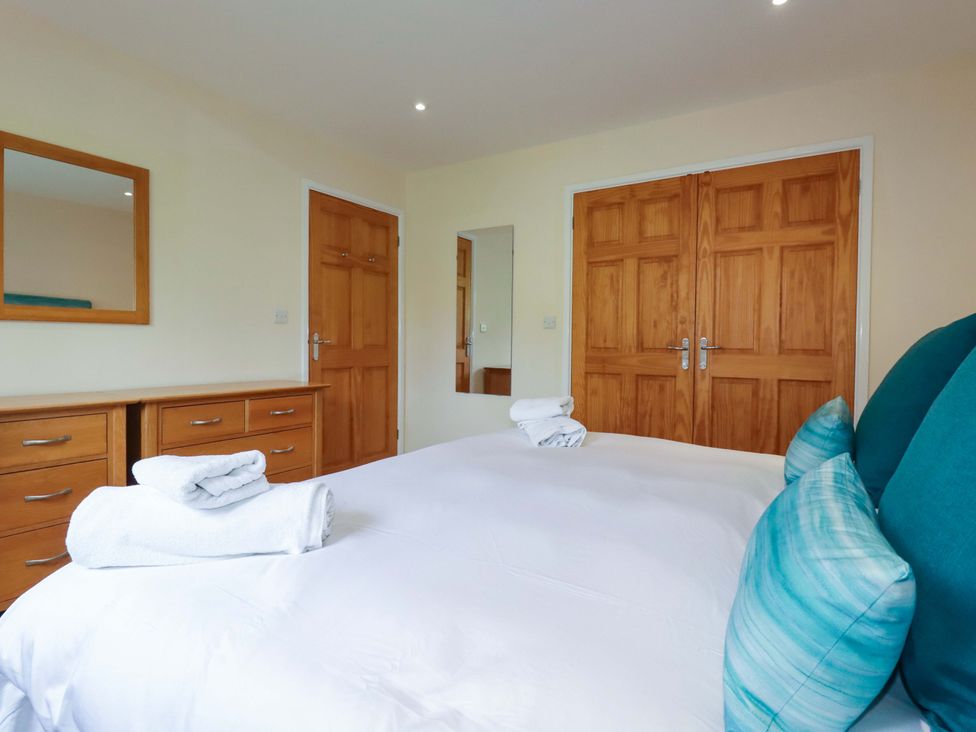 A bedroom with a bed and wooden furniture at 65 Benasa Lodge in Winnard's Perch near St Columb Major